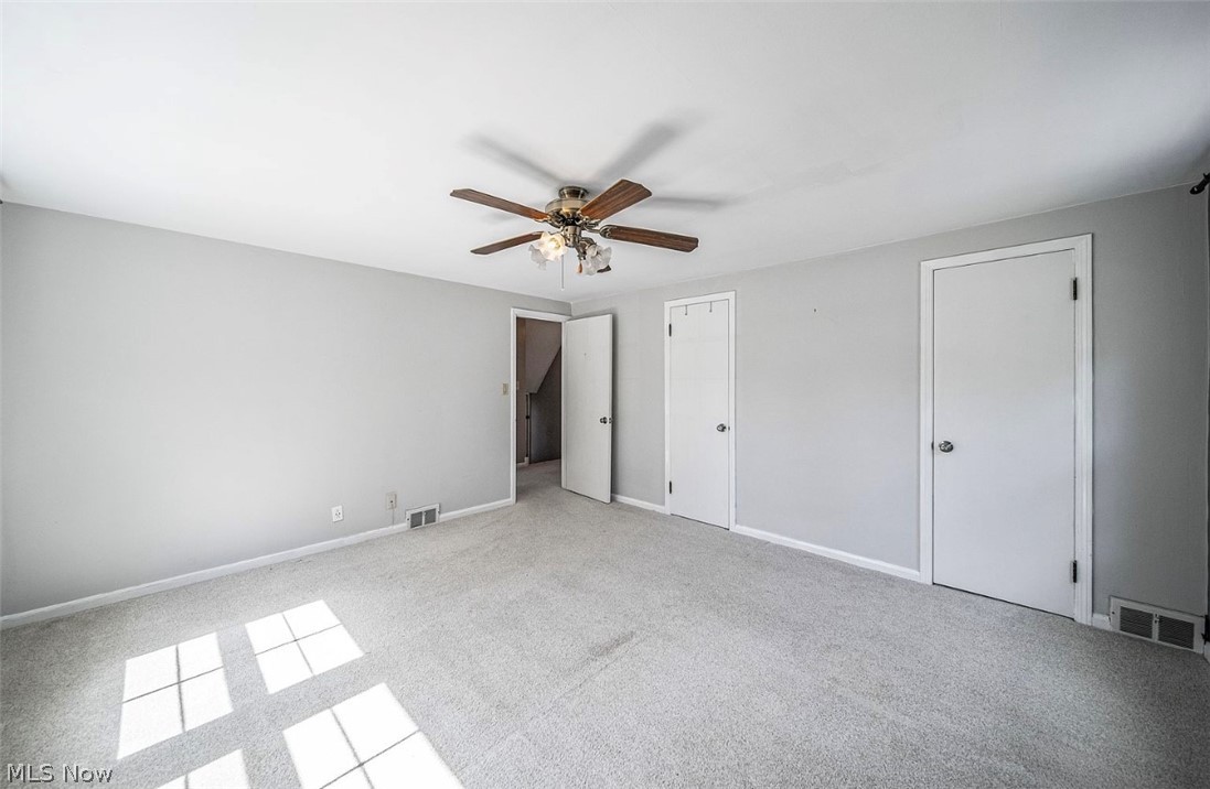 4069 Bushnell Road Cleveland, OH 44121 - Photo 23 of 39 Unfurnished bedroom featuring light colored carpet, two closets, and a ceiling fan