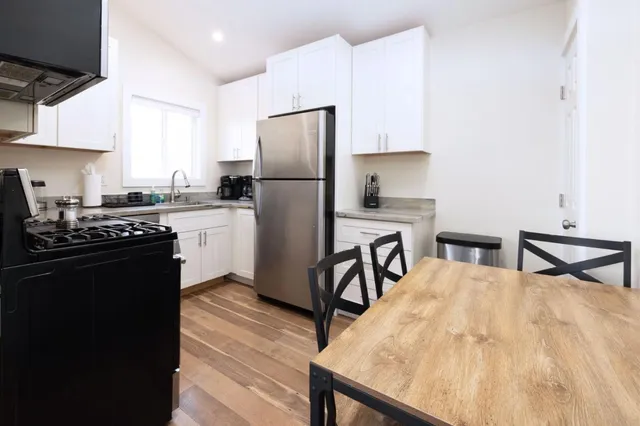 a kitchen with stainless steel appliances kitchen island a table chairs refrigerator and sink