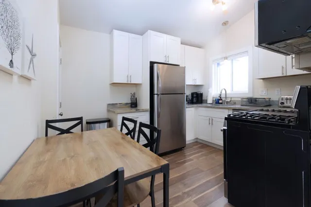 a kitchen with stainless steel appliances granite countertop a stove a refrigerator a sink a dining table and chairs