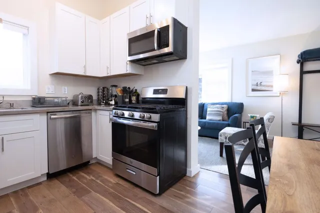 a kitchen with stainless steel appliances a stove a microwave a sink and chairs