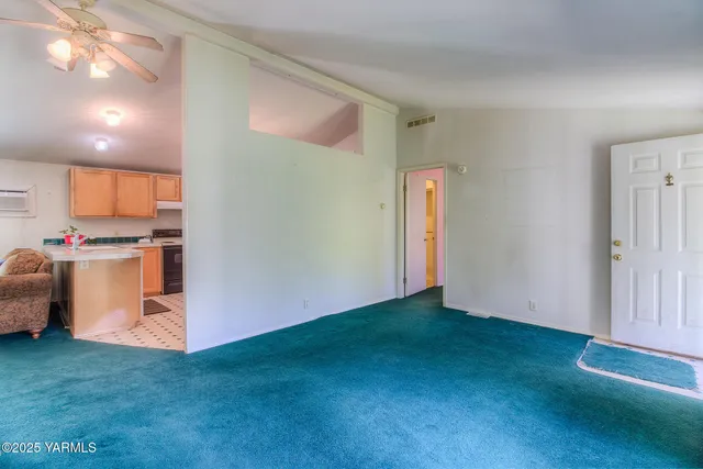 a view of an empty room with kitchen and a window