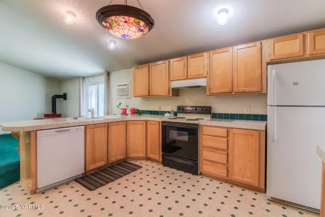 a kitchen with granite countertop a refrigerator sink stove and cabinets