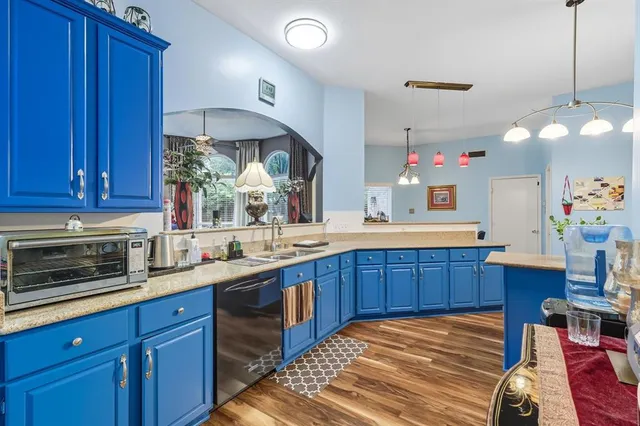 a kitchen with granite countertop a stove a sink and dishwasher wooden cabinets with wooden floor