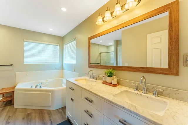 a bathroom with a granite countertop sink mirror and a bathtub