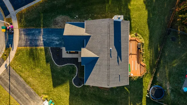 an aerial view of a house with swimming pool and large trees