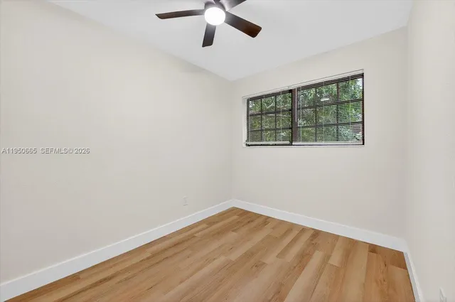 an empty room with a window and a ceiling fan