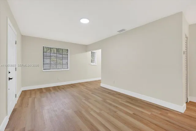 an empty room with wooden floor and windows