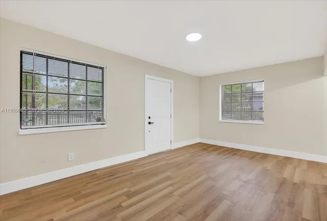 a view of an empty room with wooden floor and a window