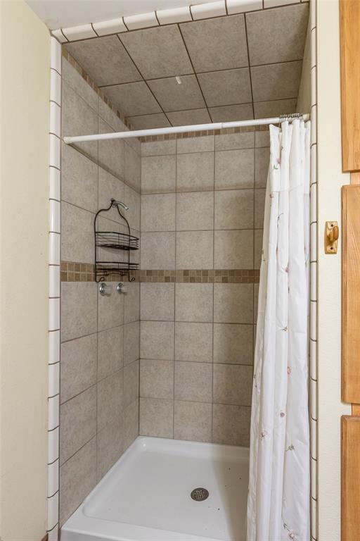 640 Ground Street Moran, TX 76464 - Photo 15 of 35 Shower stall featuring a white base, neutral-toned wall tiling, and a contrasting mosaic tile accent band