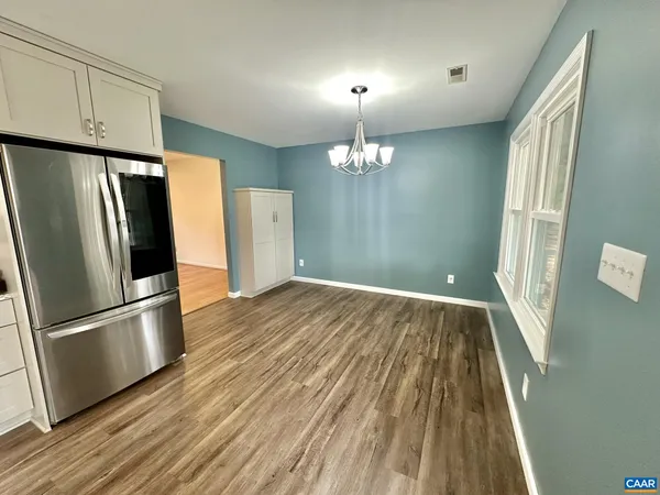 a view of a kitchen with wooden floor and refrigerator