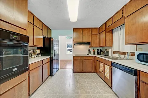 a kitchen with stainless steel appliances granite countertop a sink stove refrigerator granite counter tops wooden cabinets and a refrigerator