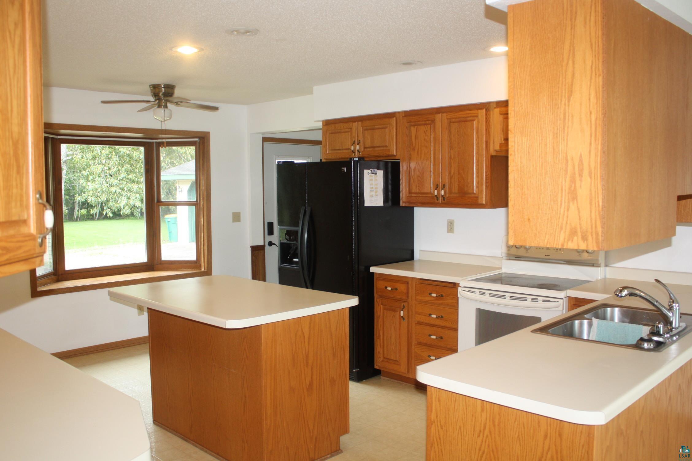 5322 East County Rd B South Range, WI 54874 - Photo 8 of 50 Kitchen with ceiling fan, white electric range, sink, a center island, and light tile patterned floors