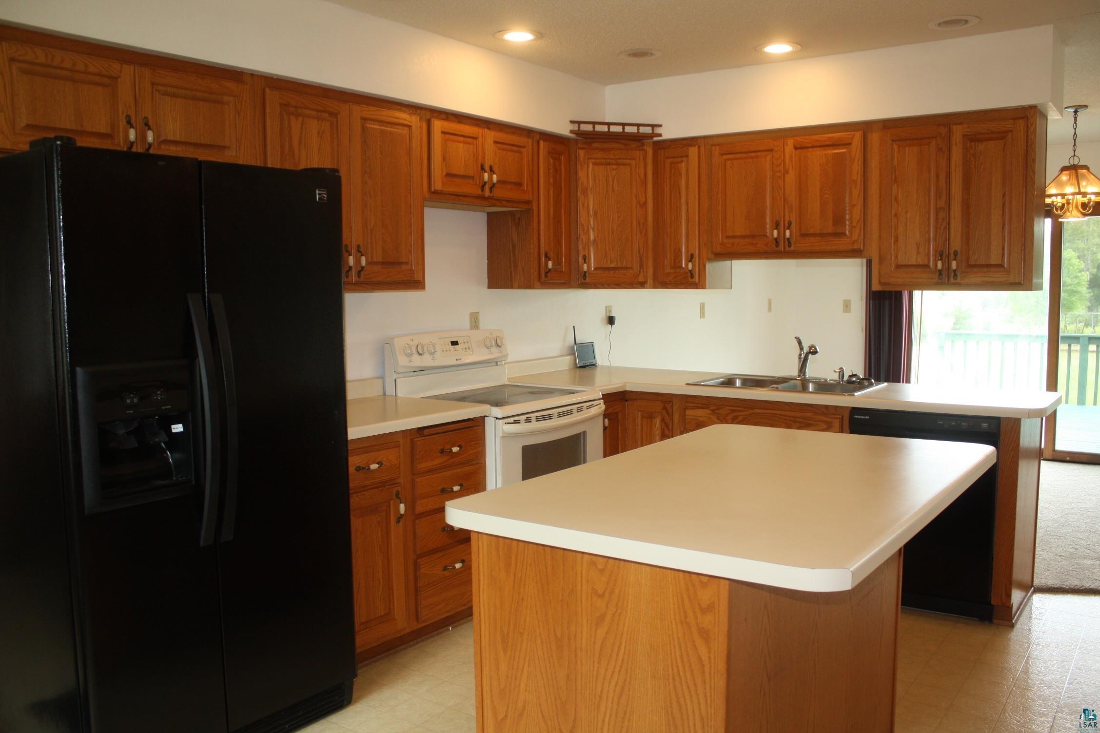 5322 East County Rd B South Range, WI 54874 - Photo 10 of 50 Kitchen with white range with electric stovetop, hanging light fixtures, light colored carpet, black fridge with ice dispenser, and sink