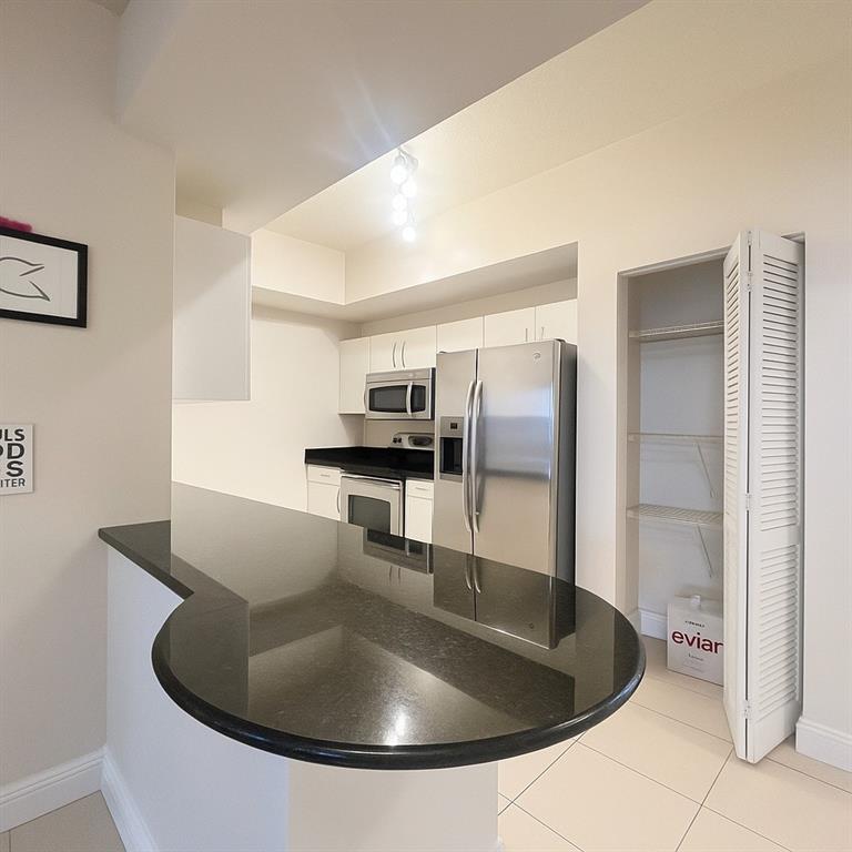 a kitchen with kitchen island stainless steel appliances a sink refrigerator and microwave