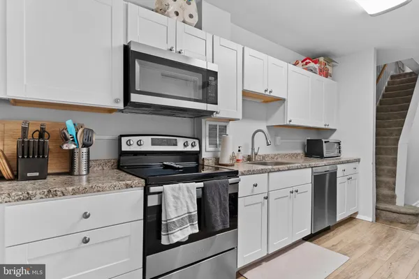 a kitchen with granite countertop a sink cabinets and stainless steel appliances