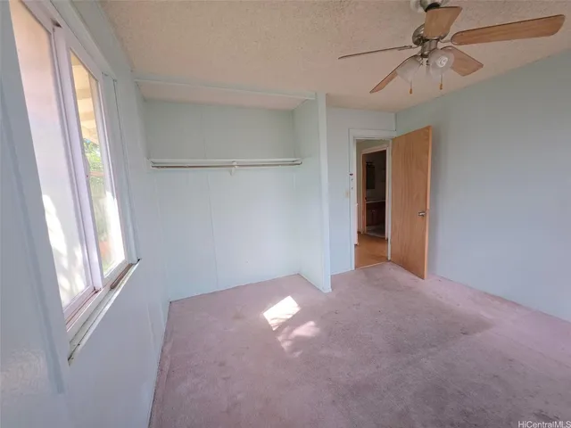 a view of empty room with window and ceiling fan