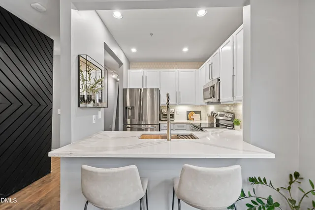 a kitchen with stainless steel appliances a table and chairs