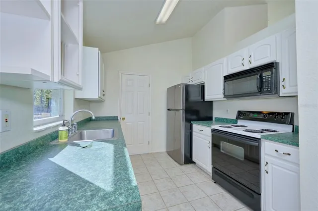 a kitchen with stainless steel appliances granite countertop a sink a counter space and a window