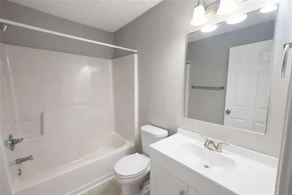 a bathroom with a bathtub shower sink vanity mirror and toilet
