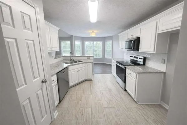 a kitchen with white cabinets appliances a sink and a window