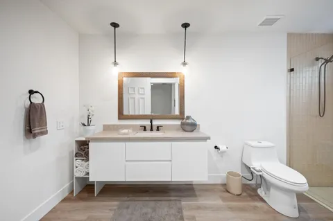 a bathroom with a granite countertop sink a toilet and shower