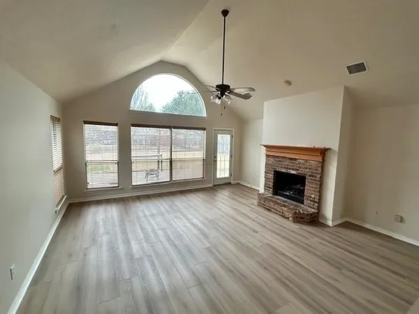 a view of empty room with wooden floor and fireplace