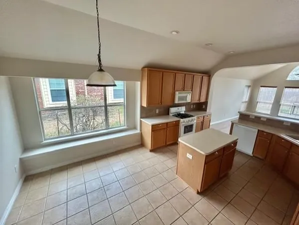 a kitchen with granite countertop a stove a sink dishwasher and a microwave oven with white cabinets