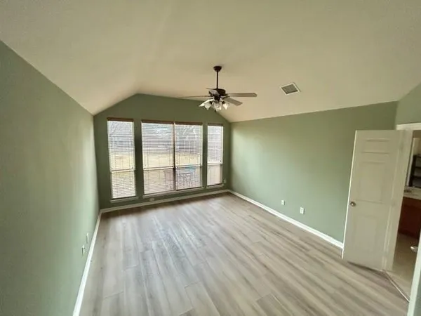 an empty room with wooden floor and windows