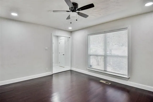 an empty room with wooden floor and windows with curtains