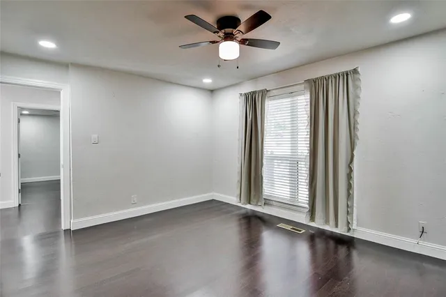 an empty room with wooden floor and a ceiling fan