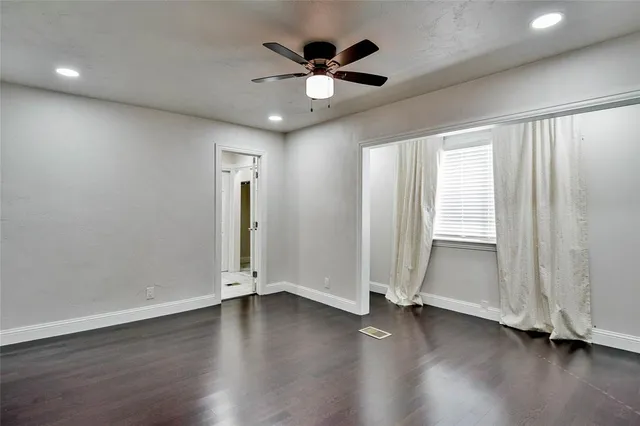 an empty room with wooden floor and a ceiling fan