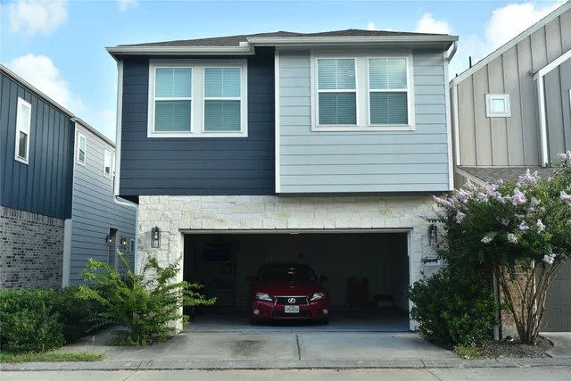 a front view of a house with plants and parking