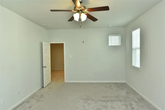 an empty room with a window and a fan