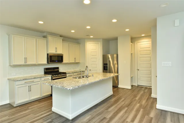 a kitchen with stainless steel appliances granite countertop a sink stove and refrigerator