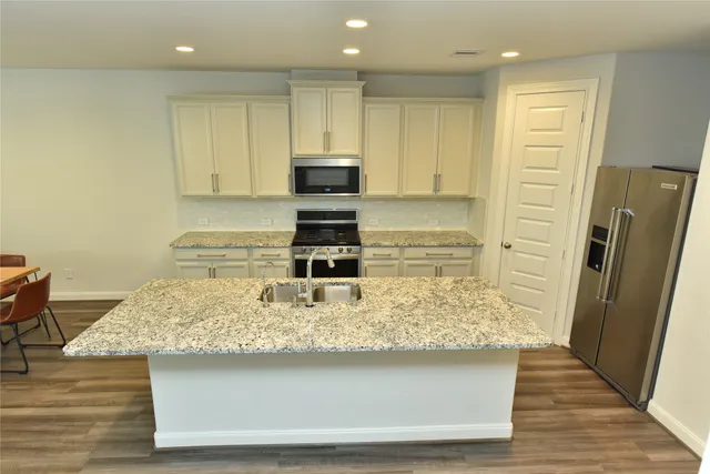 a kitchen with kitchen island granite countertop a sink stove and refrigerator