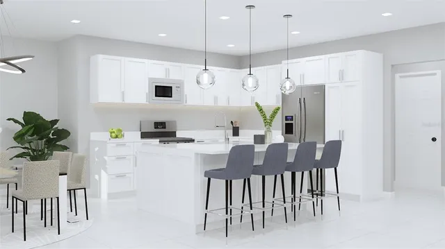 a kitchen with stainless steel appliances kitchen island granite countertop a table chairs and a refrigerator
