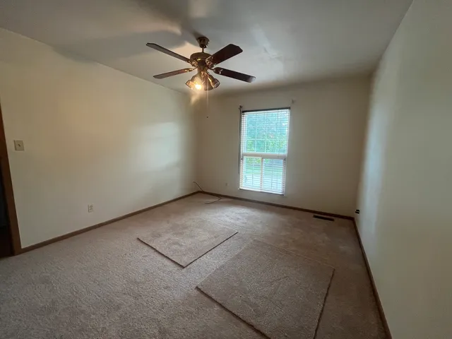 an empty room with windows and fan