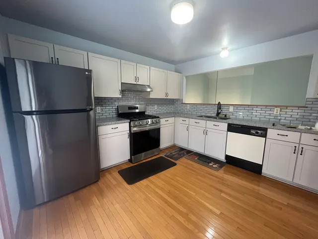 a kitchen with granite countertop stainless steel appliances a refrigerator sink and cabinets