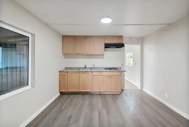 a view of empty room with wooden floor and window