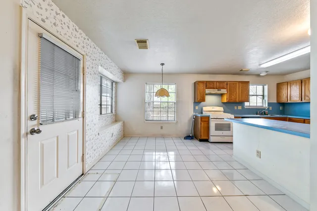 a kitchen with granite countertop a stove a sink and a refrigerator