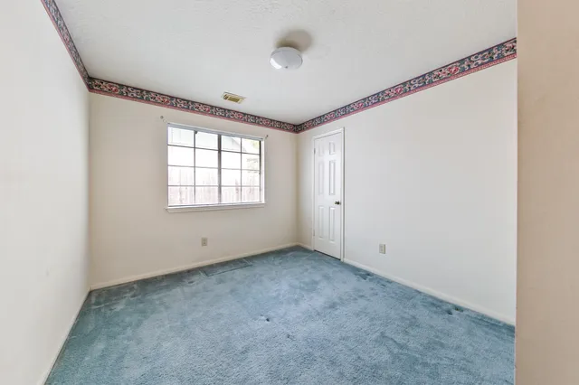a view of an empty room with windows and kitchen view