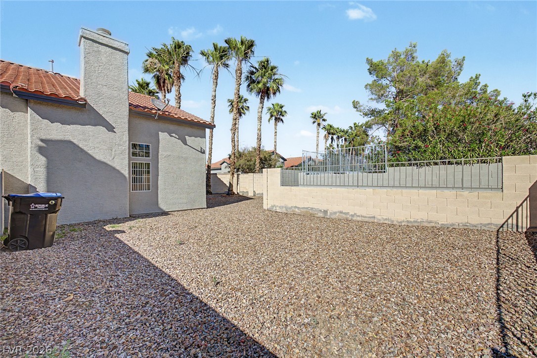 2223 Ramsgate Drive Henderson, NV 89074 - Photo 26 of 32 A low-maintenance gravel yard offers practical outdoor space, complemented by a sturdy block wall and mature palm trees.