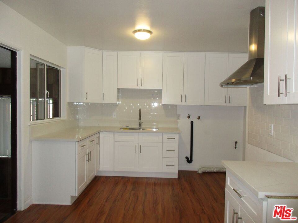 719 East 154th Street Compton, CA 90220 - Photo 10 of 32 a kitchen with sink cabinets and wooden floor