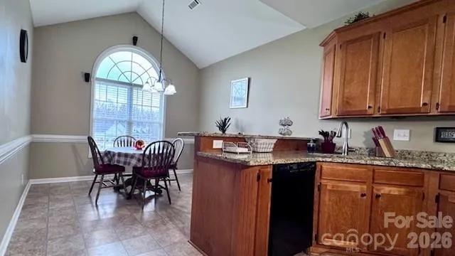 a dining hall with granite countertop a stove a sink a dining table and chairs