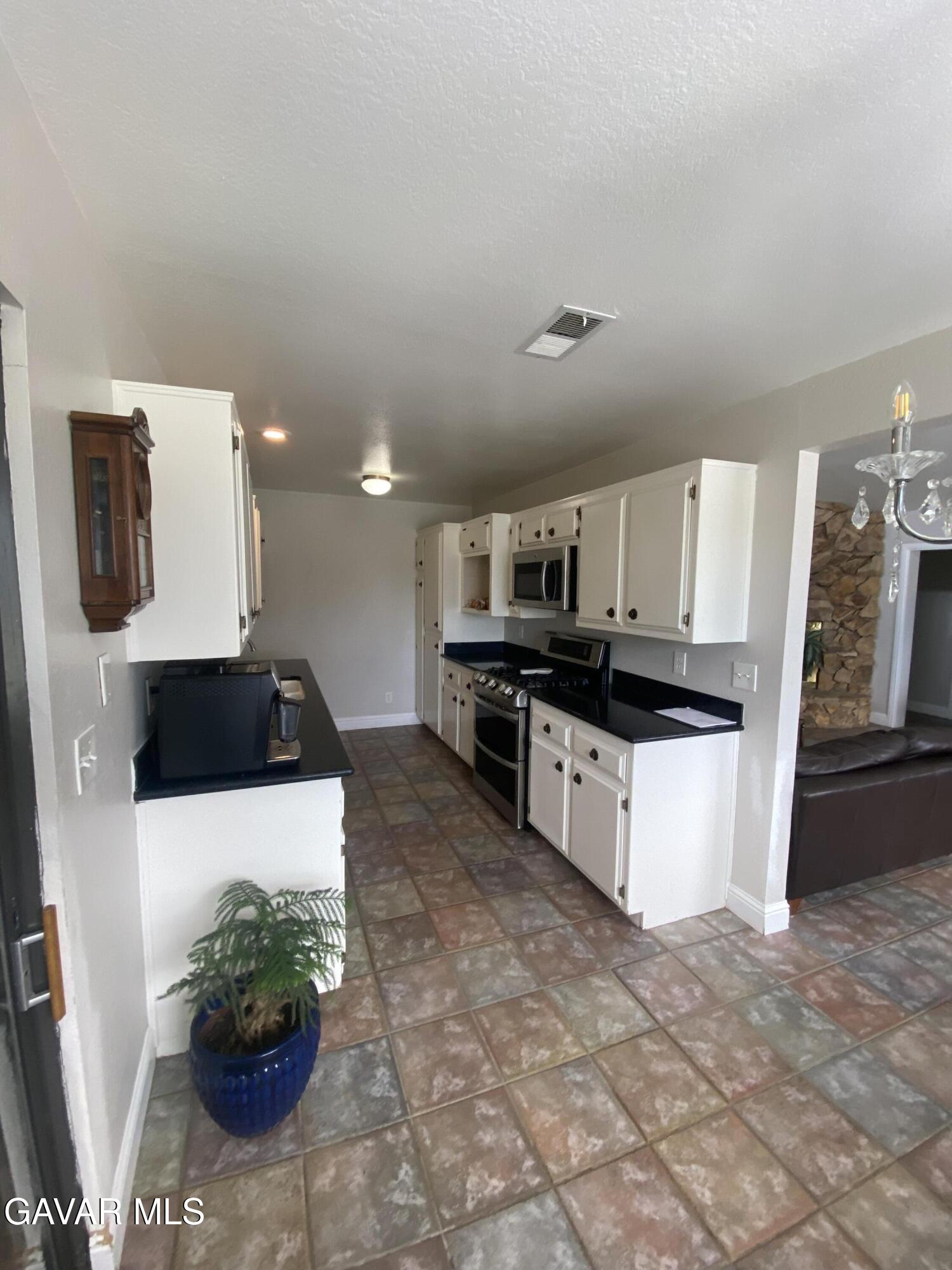 20909 Ridgeway Drive Tehachapi, CA 93561 - Photo 4 of 13 a large white kitchen with stainless steel appliances kitchen island granite countertop a sink and cabinets