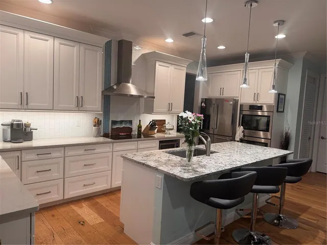 a kitchen with kitchen island granite countertop a sink cabinets and refrigerator