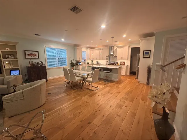 a living room with stainless steel appliances furniture and a wooden floor