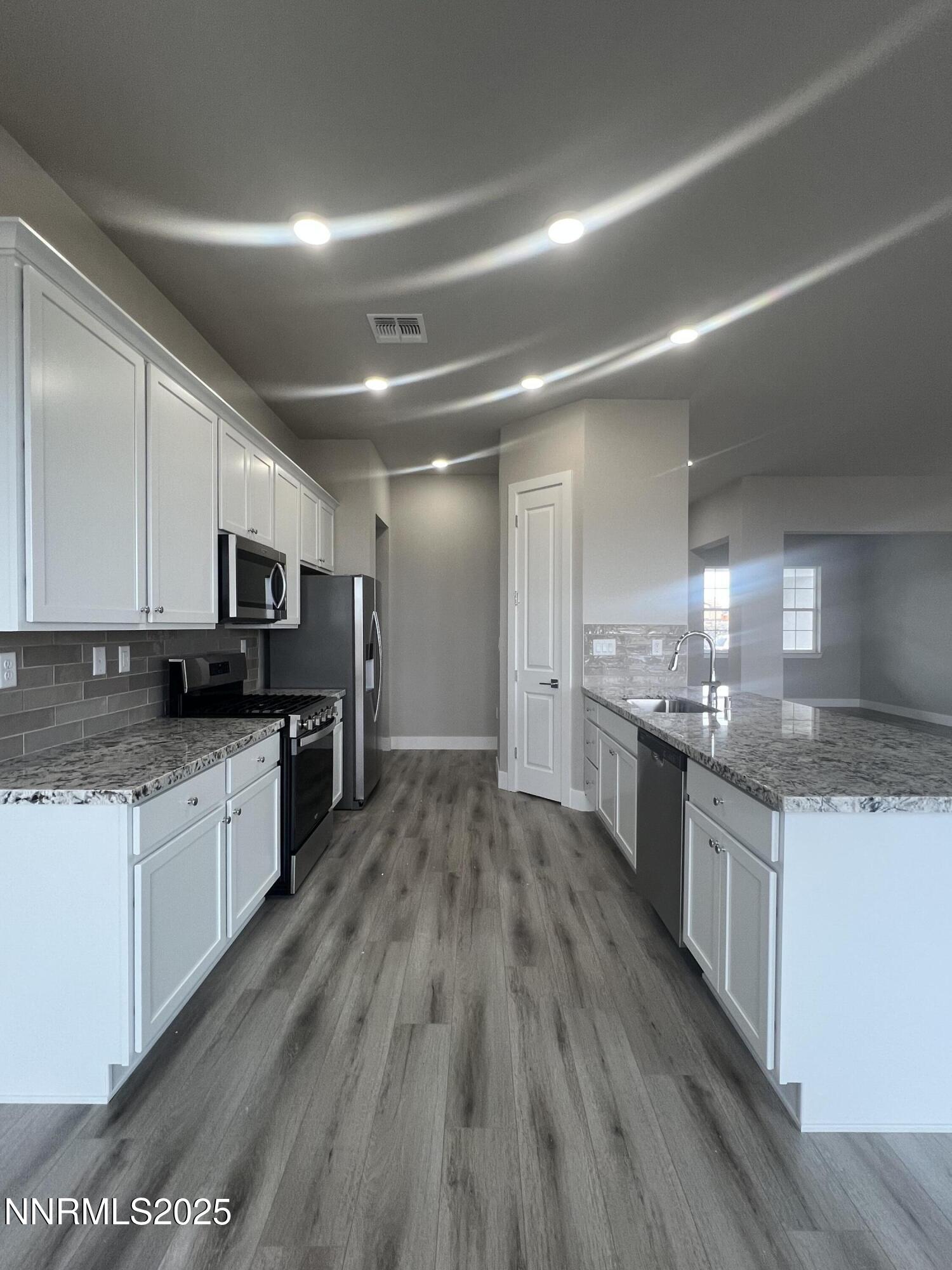 14430 Fredonia Drive Reno, NV 89506 - Photo 6 of 9 a large kitchen with stainless steel appliances granite countertop a lot of counter space and wooden floor