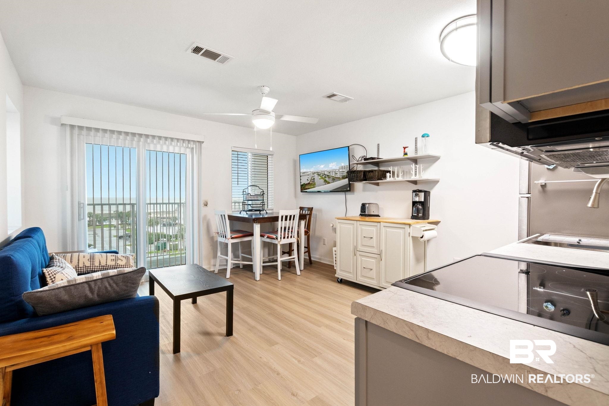 400 Plantation Road, Unit 4501 Gulf Shores, AL 36542 - Photo 5 of 30 Open-concept living area featuring wood-finish flooring, a ceiling fan, and a glass sliding door to the balcony