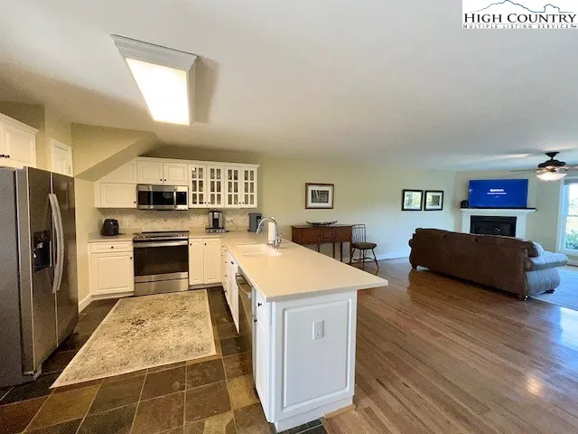 a kitchen with stainless steel appliances granite countertop a stove a sink dishwasher and a refrigerator with wooden floor